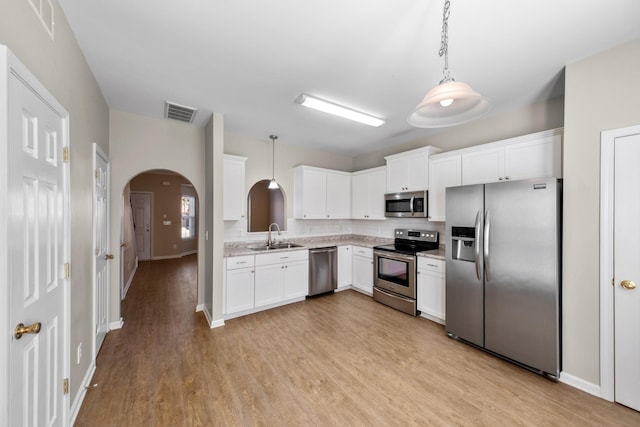 kitchen featuring sink, stainless steel appliances, white cabinetry, and hanging light fixtures