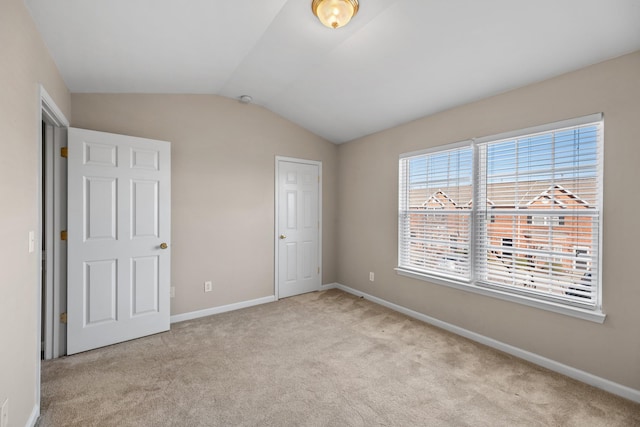 unfurnished bedroom featuring light carpet and lofted ceiling