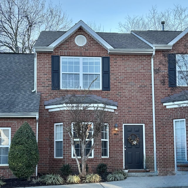 view of front of home with brick siding and roof with shingles