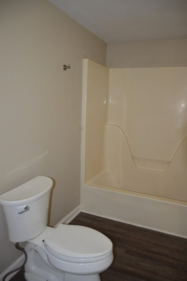 bathroom with wood-type flooring, toilet, and shower / bathtub combination