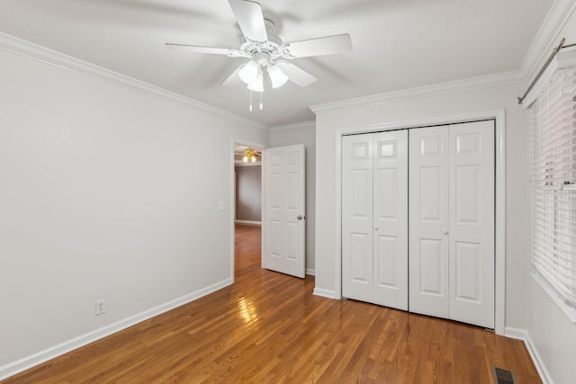 unfurnished bedroom with a closet, ceiling fan, crown molding, and hardwood / wood-style flooring