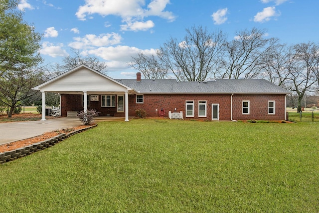 rear view of property with a lawn and a carport