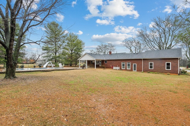 rear view of property featuring a lawn and a swimming pool