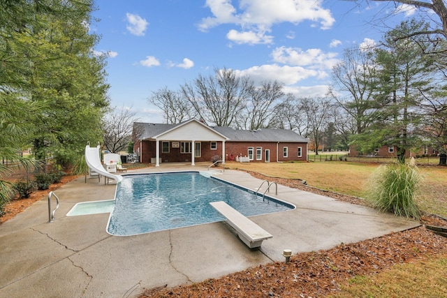 view of swimming pool featuring a patio area, a diving board, a lawn, and a water slide