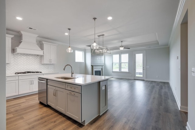 kitchen featuring ceiling fan, sink, a center island with sink, white cabinets, and custom range hood