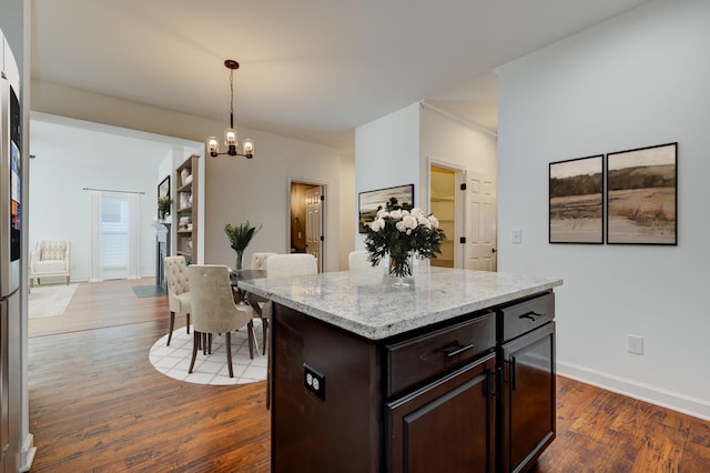 kitchen with a kitchen island, dark hardwood / wood-style floors, decorative light fixtures, a notable chandelier, and dark brown cabinets