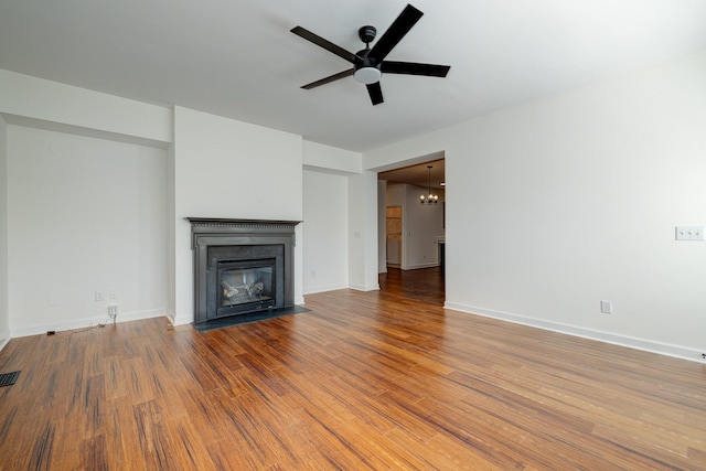 unfurnished living room with ceiling fan with notable chandelier and hardwood / wood-style flooring