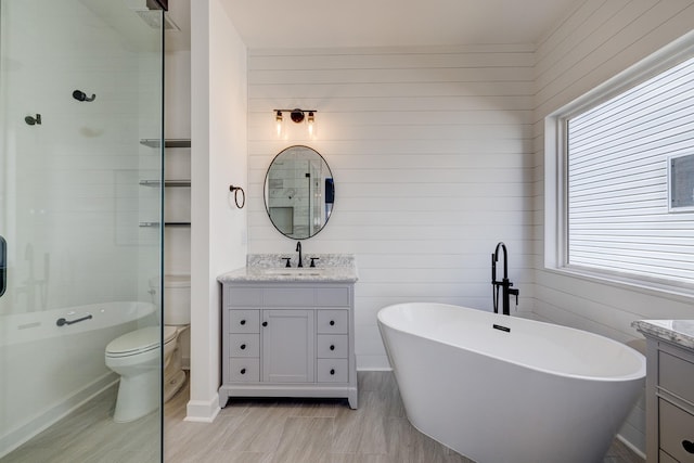 bathroom with toilet, vanity, and a tub to relax in