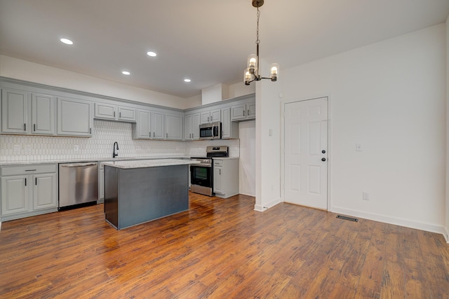 kitchen with decorative light fixtures, a center island, appliances with stainless steel finishes, gray cabinets, and a notable chandelier