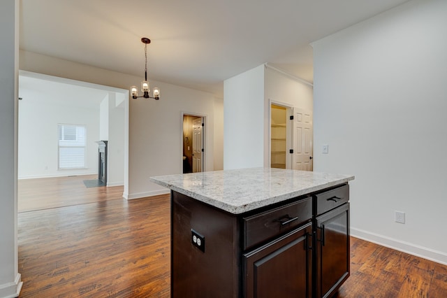 kitchen featuring dark wood-type flooring, dark brown cabinetry, a kitchen island, decorative light fixtures, and a chandelier