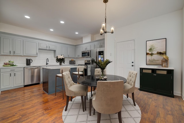 dining room with a notable chandelier, dark wood-type flooring, and sink