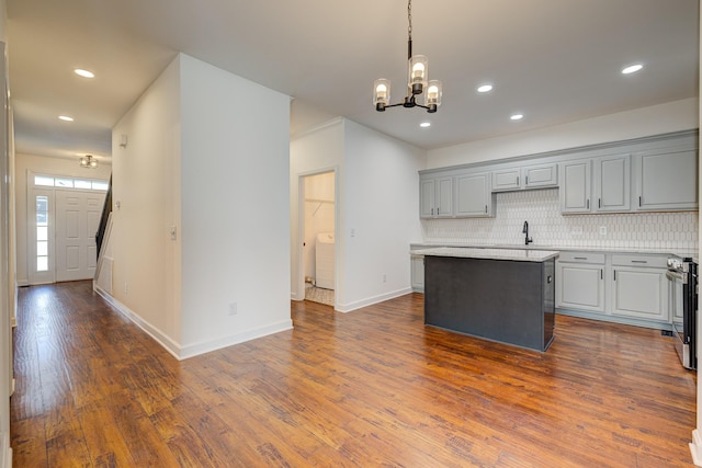 kitchen with an inviting chandelier, a center island, gray cabinets, and tasteful backsplash