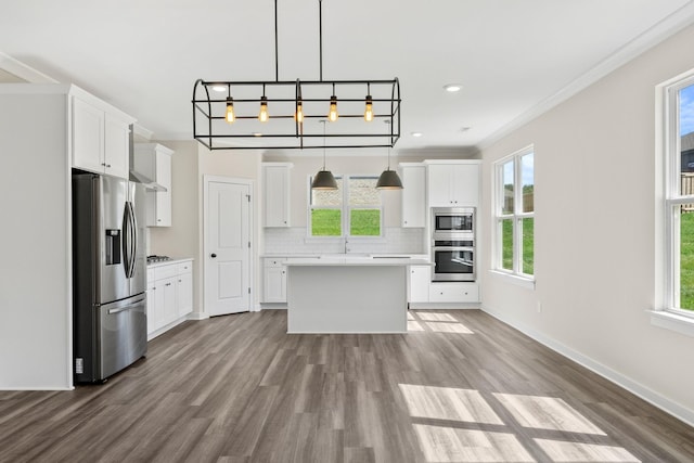 kitchen featuring appliances with stainless steel finishes, a center island, decorative light fixtures, and white cabinetry