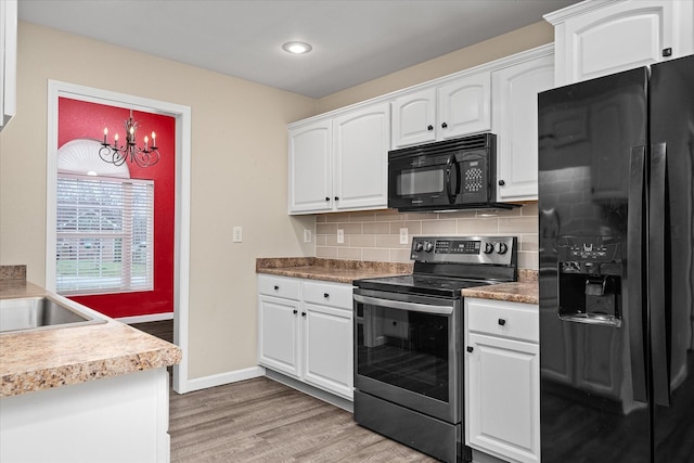 kitchen featuring black appliances, white cabinets, backsplash, and an inviting chandelier