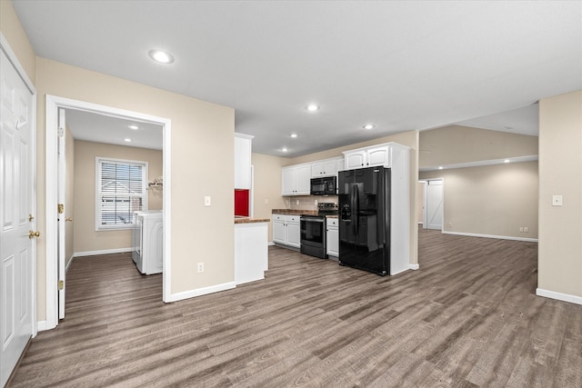 kitchen featuring backsplash, black appliances, hardwood / wood-style flooring, washer / dryer, and white cabinetry