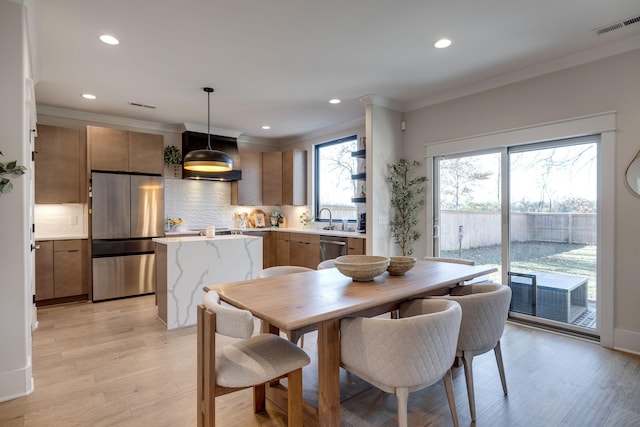 dining space featuring light hardwood / wood-style floors, sink, and crown molding