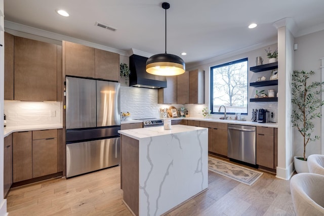 kitchen featuring tasteful backsplash, wall chimney exhaust hood, stainless steel appliances, a center island, and hanging light fixtures