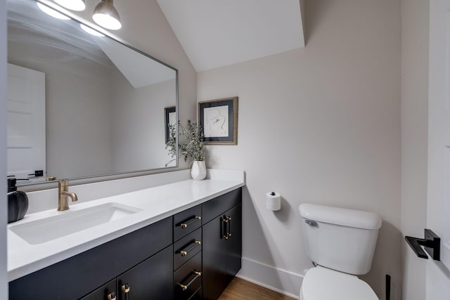 bathroom featuring wood-type flooring, vanity, toilet, and lofted ceiling