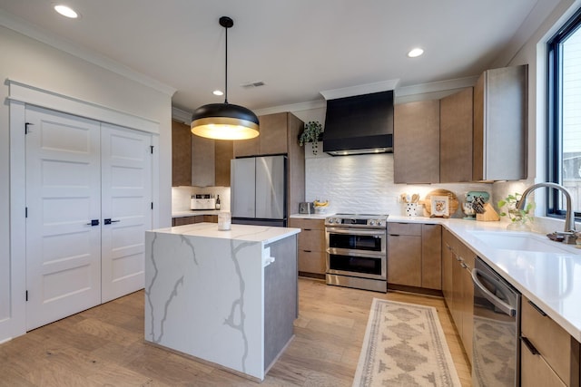 kitchen with sink, wall chimney exhaust hood, appliances with stainless steel finishes, tasteful backsplash, and a kitchen island