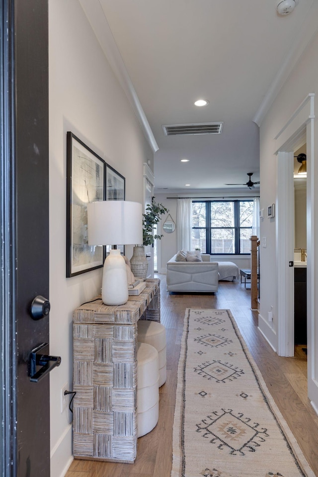 hall with light wood-type flooring and crown molding