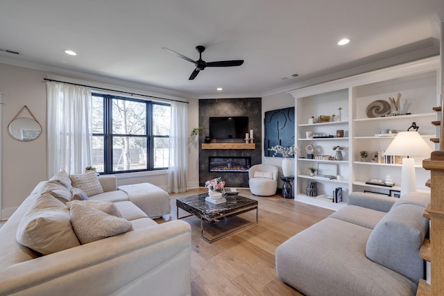 living room with a fireplace, light hardwood / wood-style floors, ceiling fan, and ornamental molding