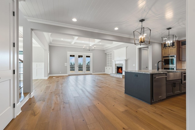 kitchen featuring beamed ceiling, hanging light fixtures, coffered ceiling, a kitchen island with sink, and light wood-type flooring