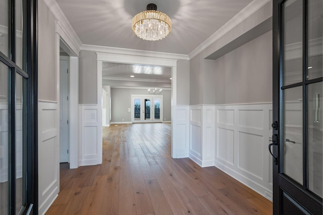 foyer entrance featuring ornamental molding, hardwood / wood-style floors, a chandelier, and french doors