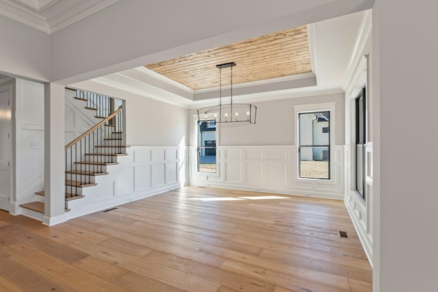 interior space featuring a tray ceiling, crown molding, light hardwood / wood-style floors, and a chandelier