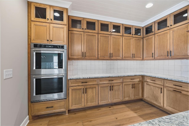 kitchen featuring tasteful backsplash, light stone counters, and double oven