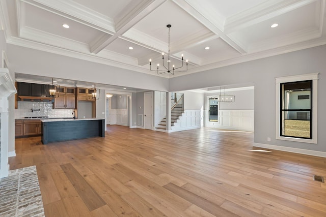 unfurnished living room featuring beamed ceiling, coffered ceiling, and a notable chandelier