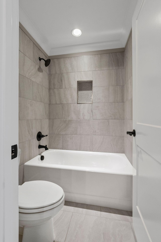 bathroom featuring ornamental molding, toilet, tiled shower / bath combo, and tile patterned flooring