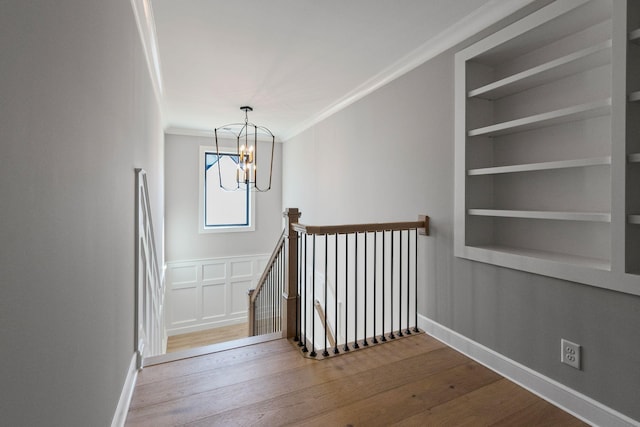 stairs featuring an inviting chandelier, hardwood / wood-style floors, ornamental molding, and built in features