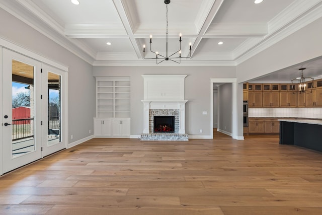 unfurnished living room with an inviting chandelier, beam ceiling, a fireplace, and coffered ceiling