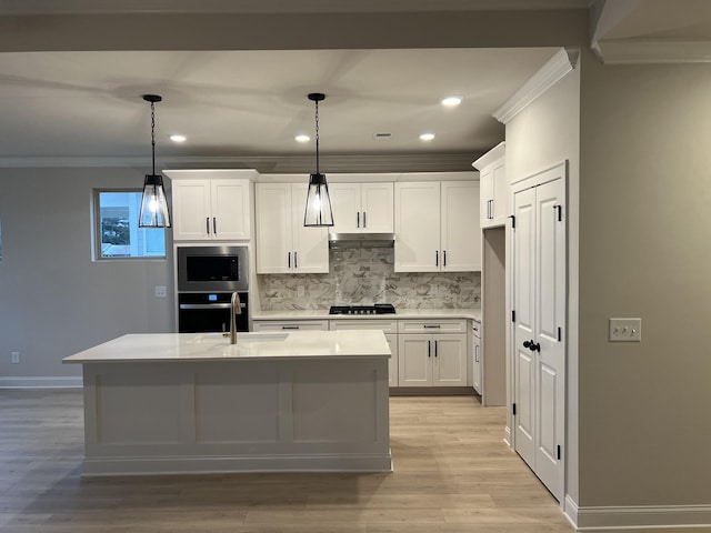 kitchen with pendant lighting, white cabinets, oven, and sink