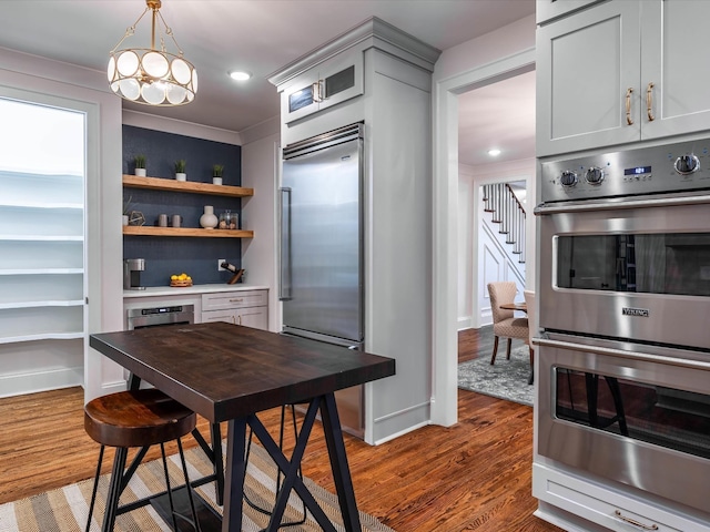 kitchen featuring appliances with stainless steel finishes, dark hardwood / wood-style flooring, decorative light fixtures, an inviting chandelier, and gray cabinets