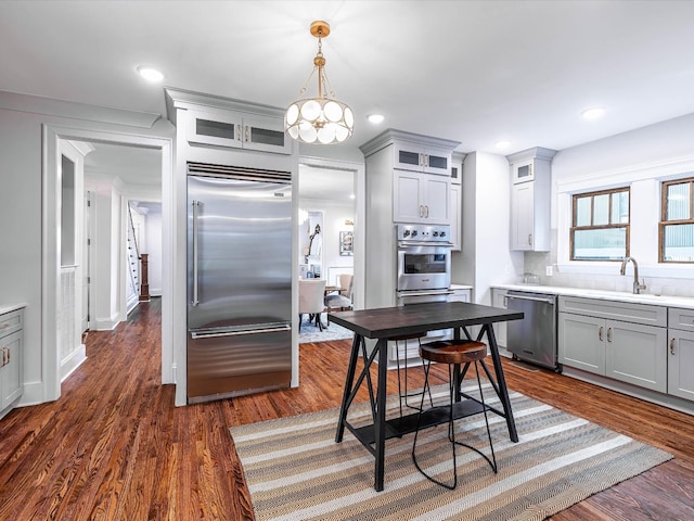 kitchen featuring gray cabinetry, dark wood-type flooring, hanging light fixtures, tasteful backsplash, and stainless steel appliances