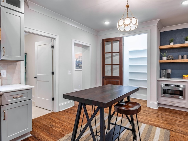 dining space with french doors, light wood-type flooring, crown molding, and a chandelier