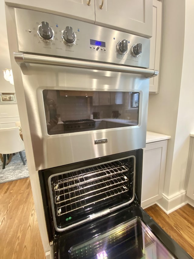 interior details featuring stainless steel double oven, light hardwood / wood-style floors, and butcher block countertops