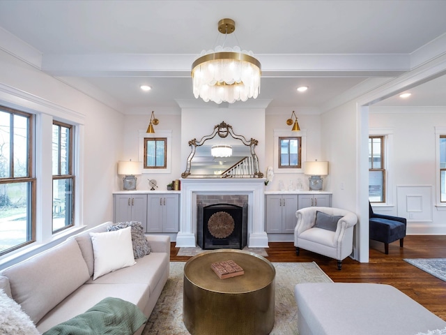 living room featuring beam ceiling, crown molding, dark hardwood / wood-style floors, and an inviting chandelier