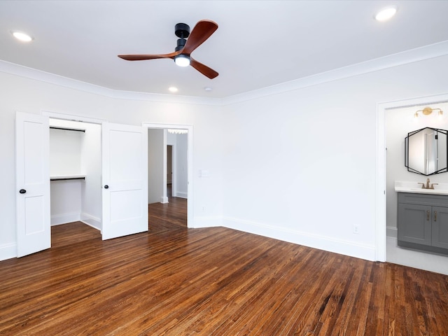 unfurnished bedroom featuring connected bathroom, ceiling fan, dark wood-type flooring, crown molding, and a closet