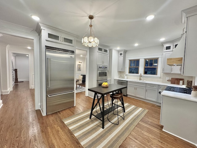 kitchen with sink, hanging light fixtures, light hardwood / wood-style flooring, tasteful backsplash, and stainless steel appliances