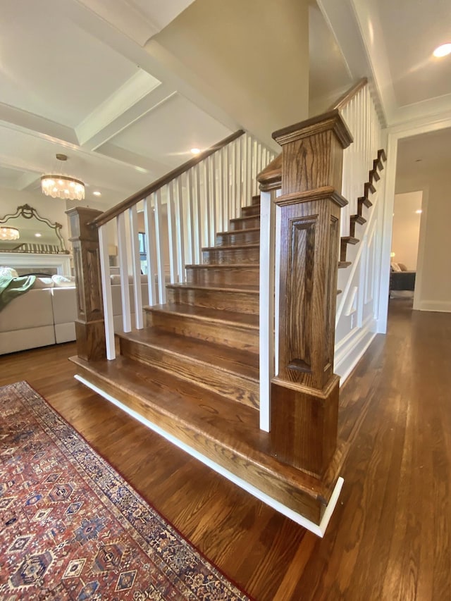 staircase featuring beam ceiling, hardwood / wood-style floors, and an inviting chandelier