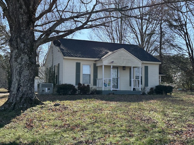 view of front of property with covered porch, central AC unit, and a front yard