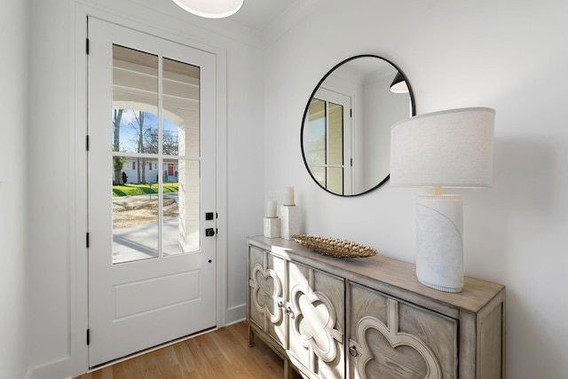 entryway with ornamental molding and light hardwood / wood-style flooring