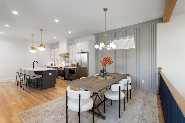 dining area featuring beam ceiling, light hardwood / wood-style floors, a notable chandelier, and sink