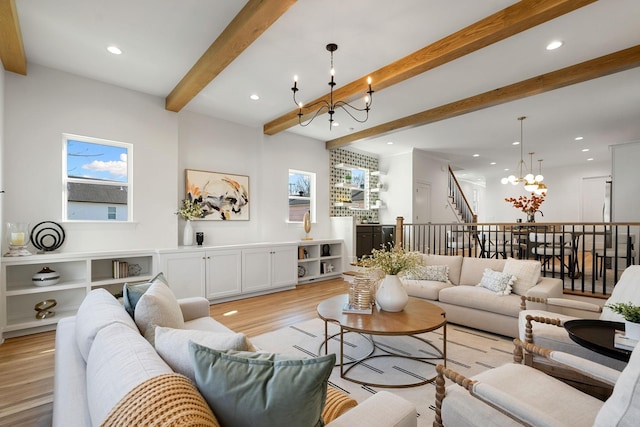 living room featuring beamed ceiling, light hardwood / wood-style flooring, a wealth of natural light, and a chandelier