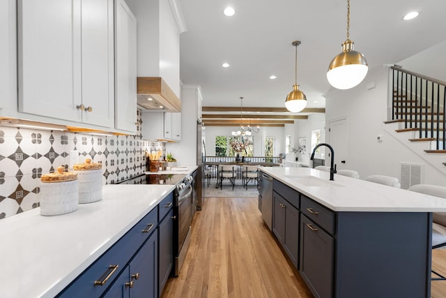 kitchen featuring white cabinetry, sink, blue cabinets, pendant lighting, and appliances with stainless steel finishes