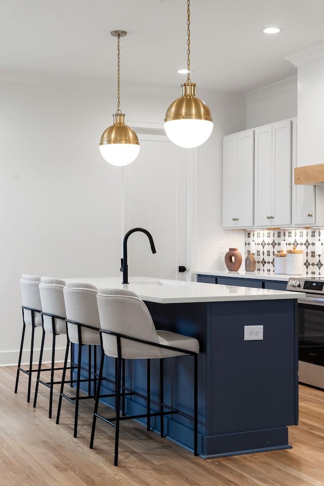 kitchen with white cabinets, stainless steel stove, decorative light fixtures, and a kitchen island