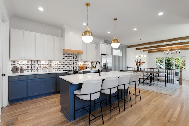 kitchen with stainless steel appliances, blue cabinetry, a notable chandelier, white cabinets, and hanging light fixtures