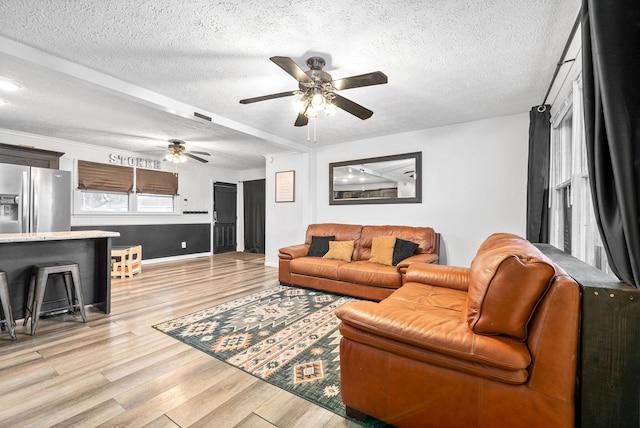 living room with ceiling fan, light hardwood / wood-style floors, and a textured ceiling